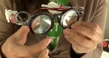 Hands holding DIY glasses with magnifying lenses.