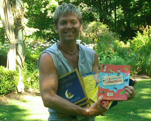 Person displaying books in sunny backyard
