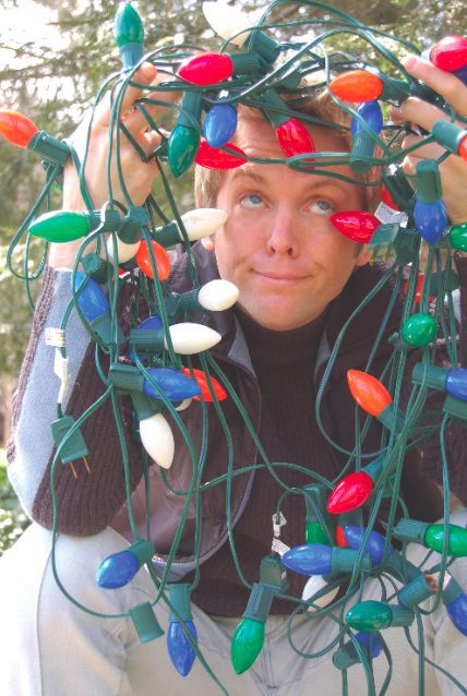 Person tangled in colorful Christmas lights