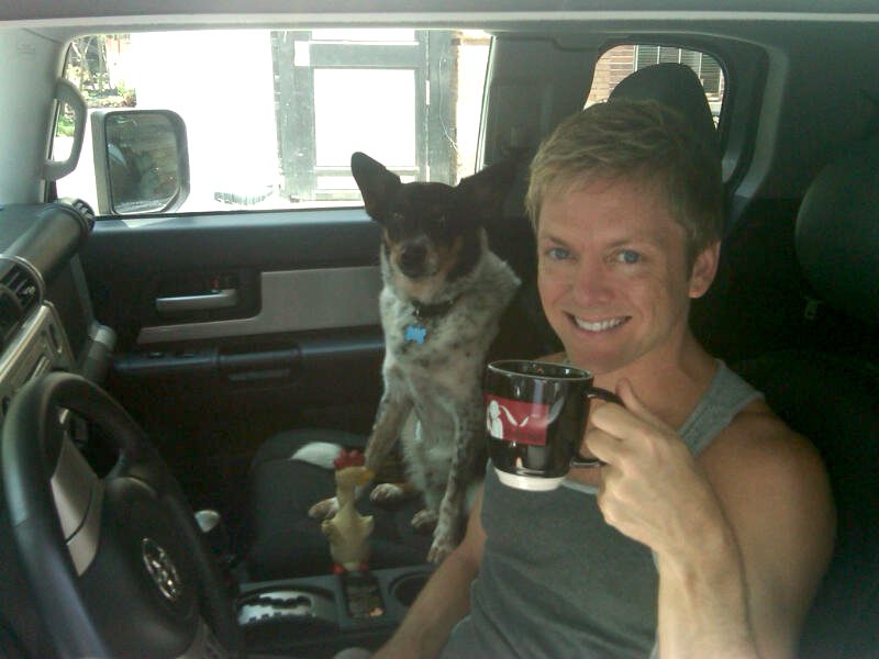 Man with dog in car holding mug