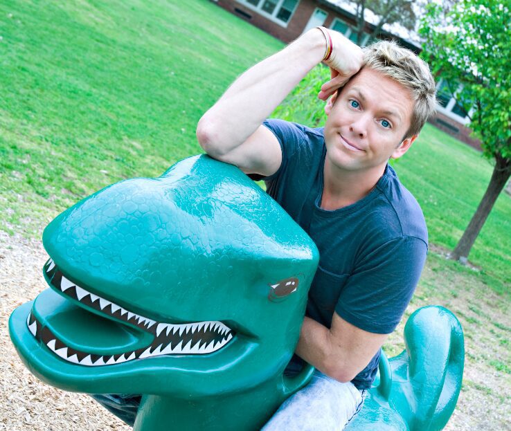 Smiling individual on a plastic dinosaur ride