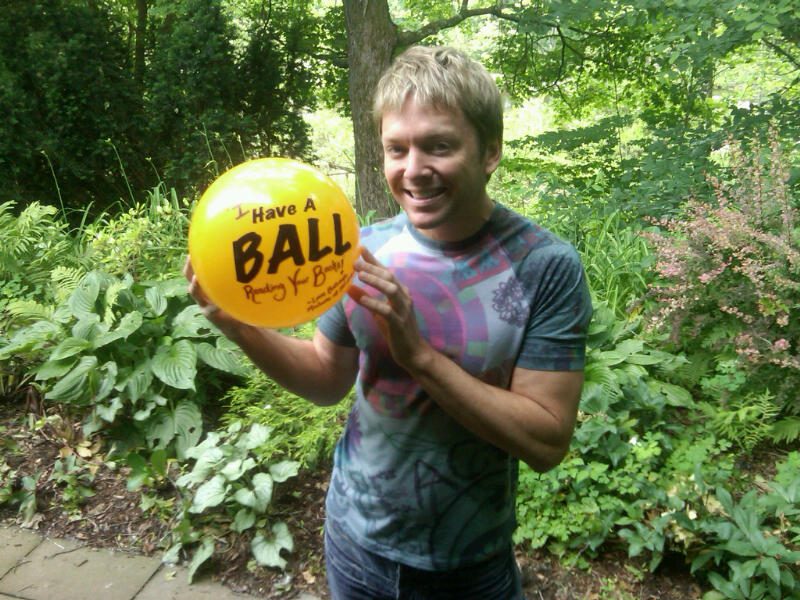 Man holding a yellow balloon outdoors