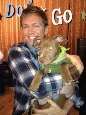 Person with plaid shirt hugging a puppy