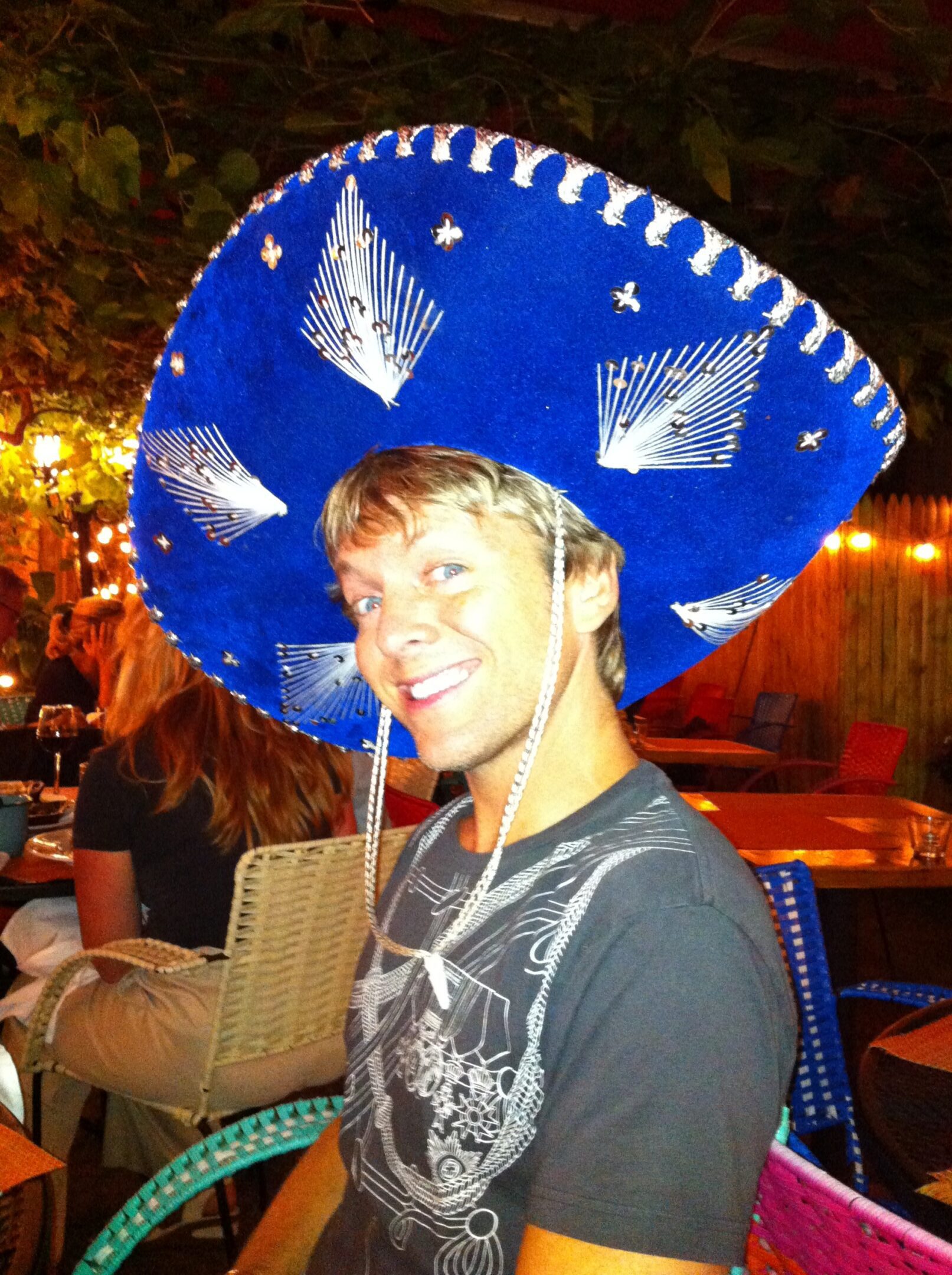 Man in sombrero at outdoor restaurant.