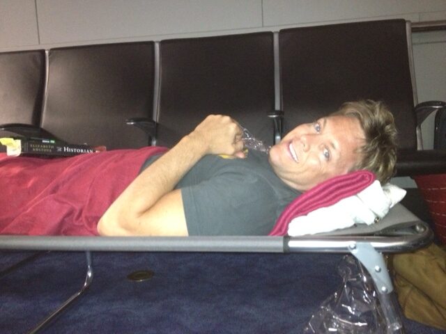 Man lying on an airport bench