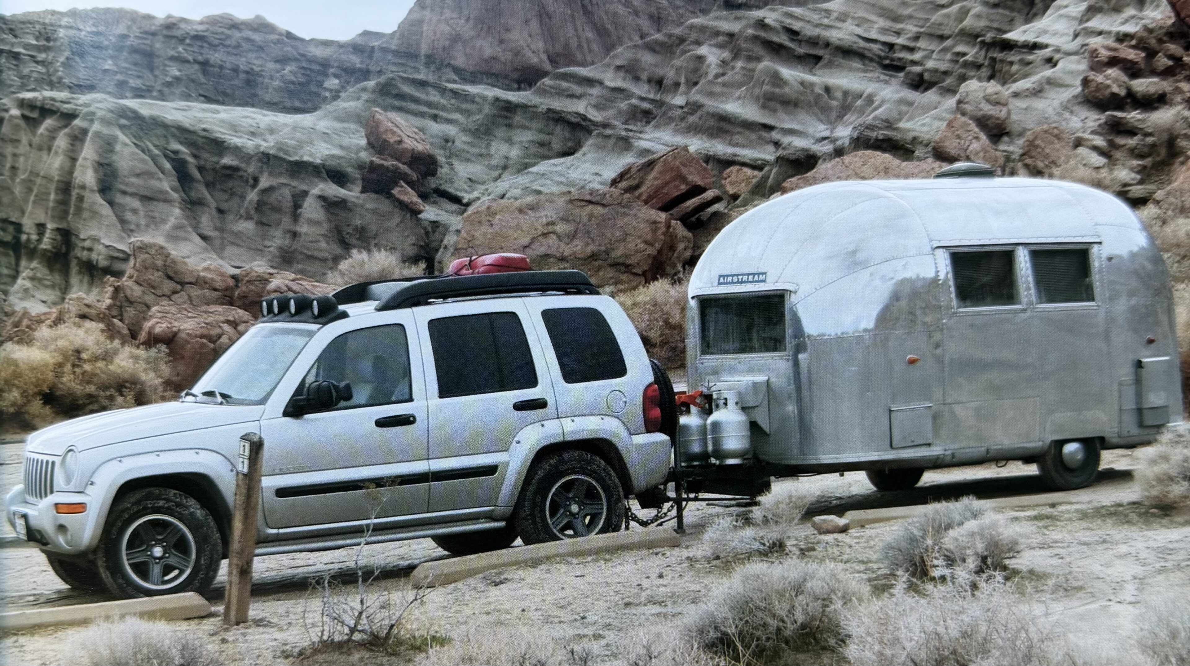 SUV towing a trailer in rocky landscape.