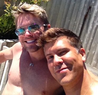 Two smiling men outdoors in sunlight.