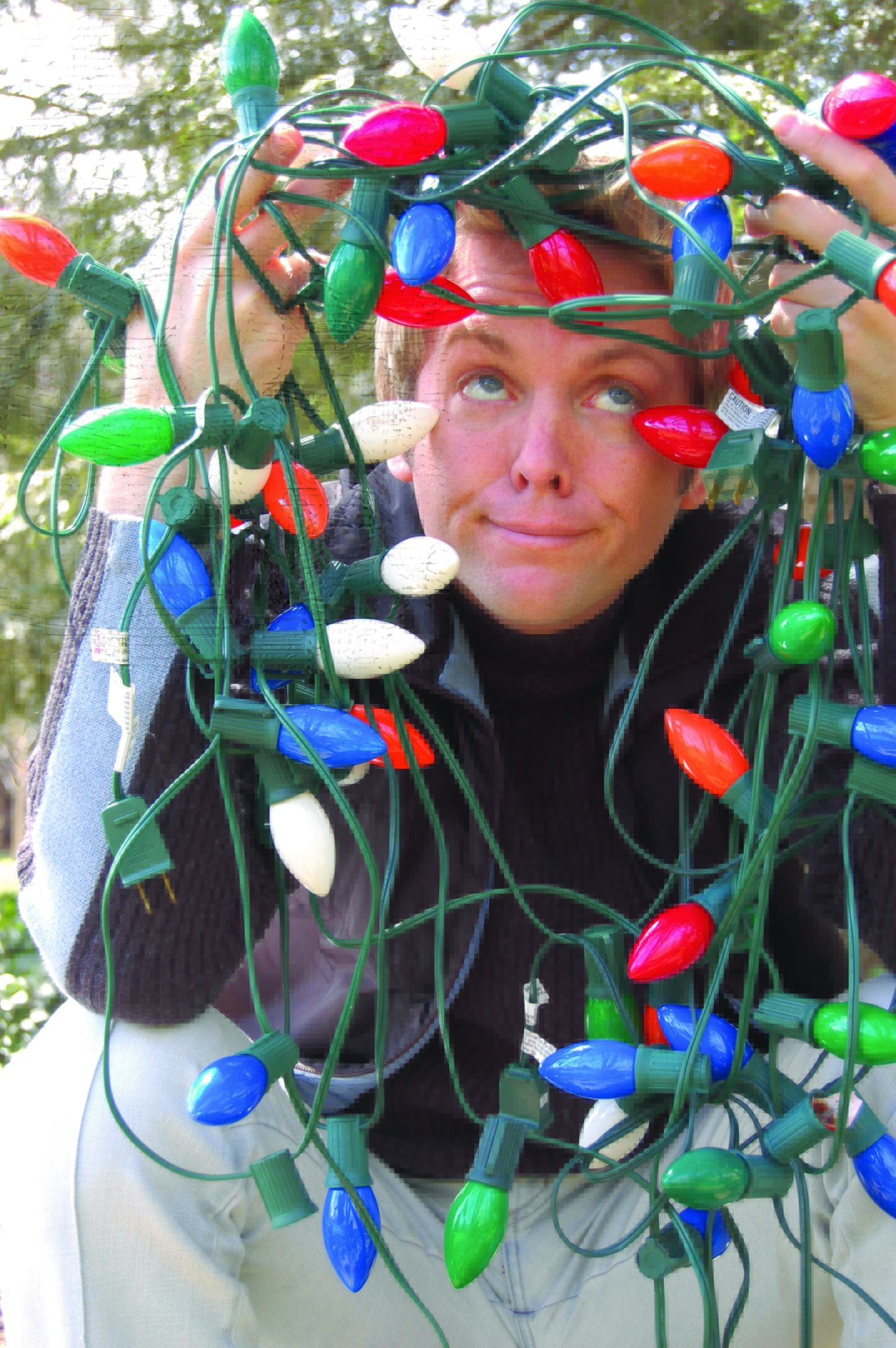 Person tangled in colorful Christmas lights.