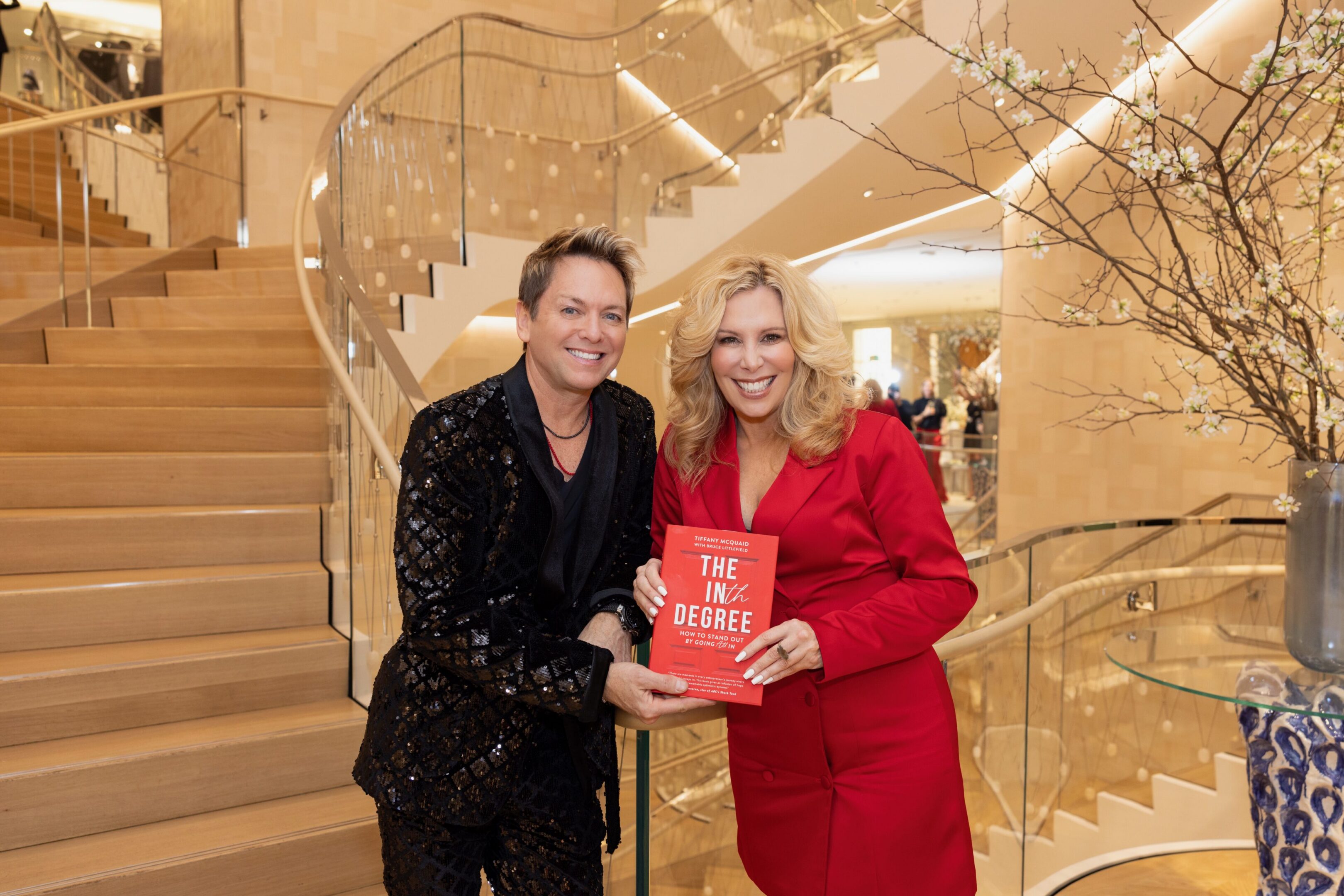 Two people holding a red book, smiling.