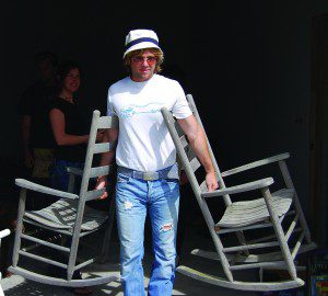 Man carrying two wooden rocking chairs