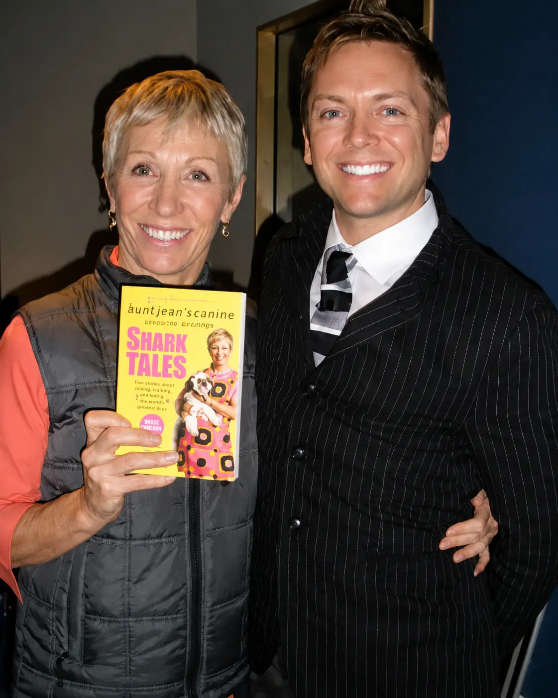 Two people smiling, holding a book.