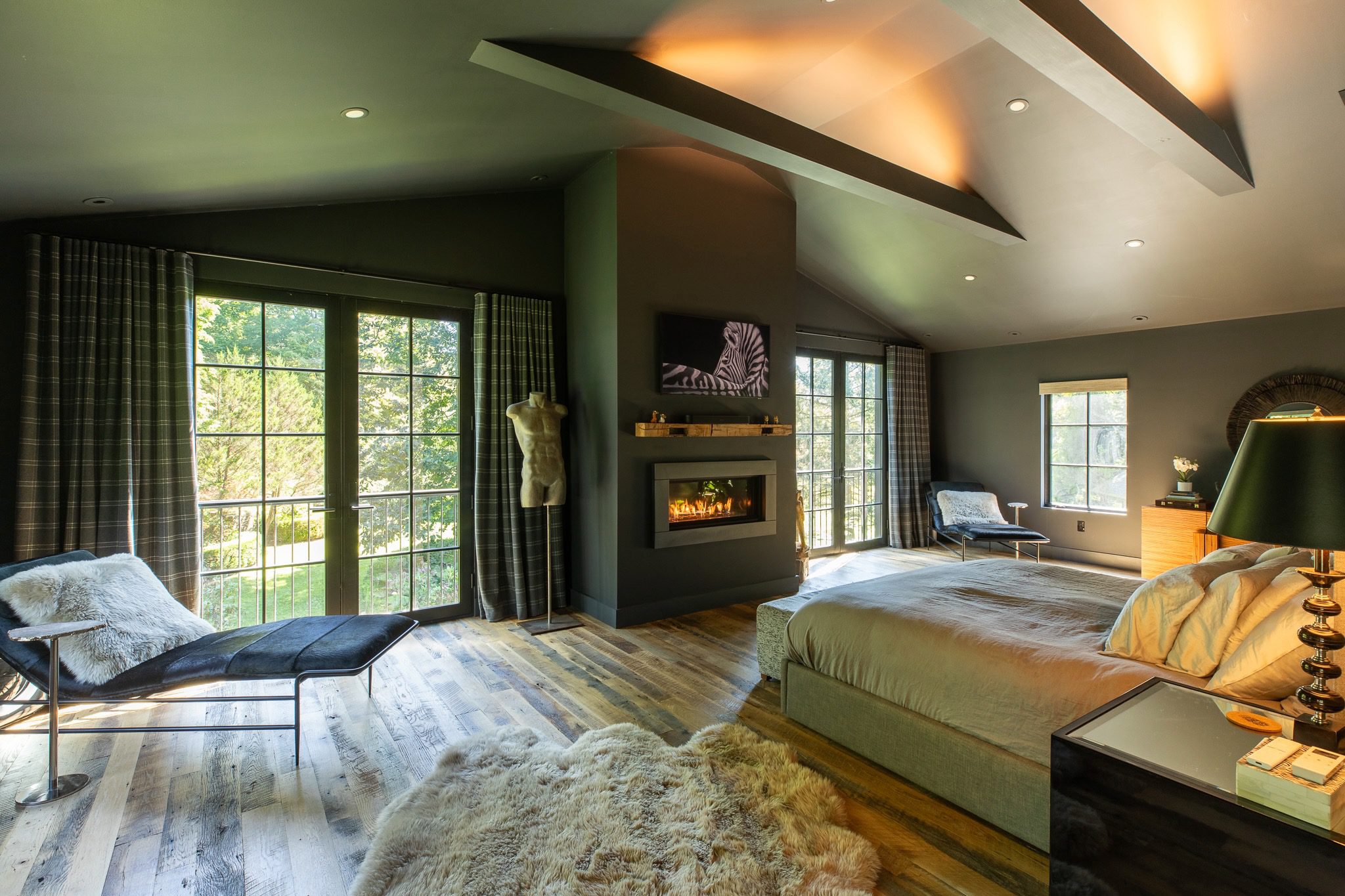 Spacious bedroom with fireplace and large windows.