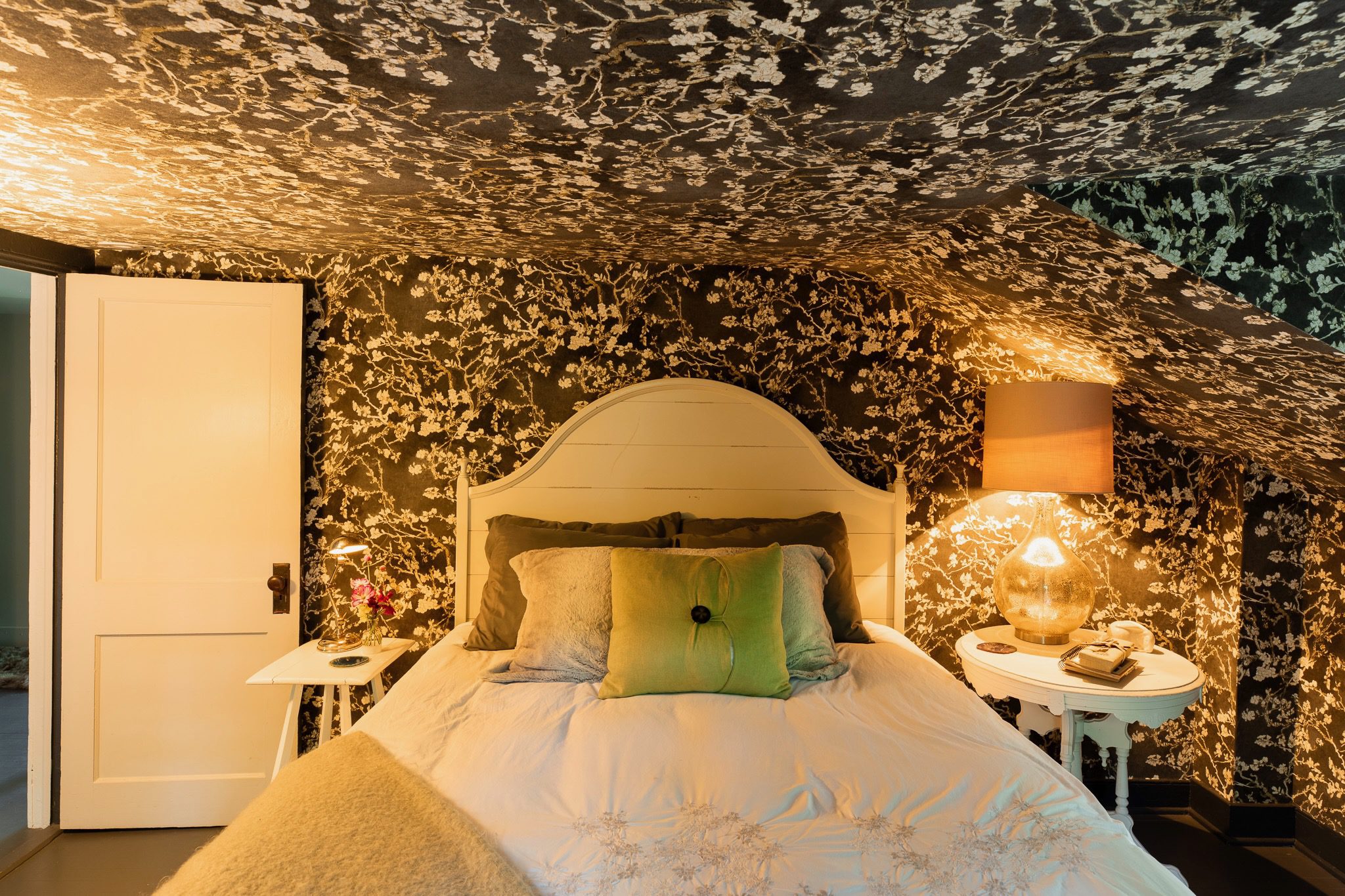 Cozy bedroom with floral wallpaper and lighting.