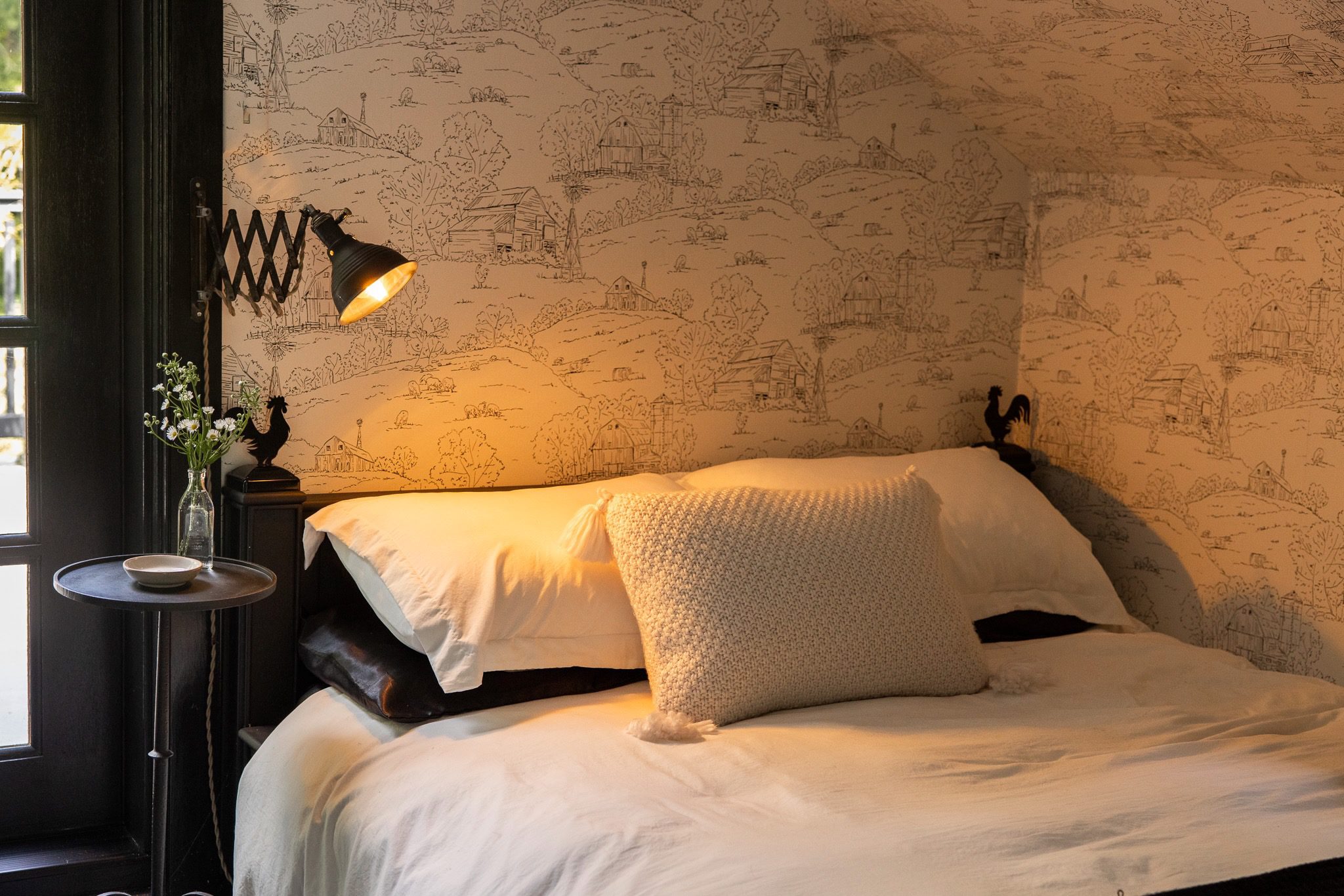 Cozy bedroom with decorative wallpaper and lamp.