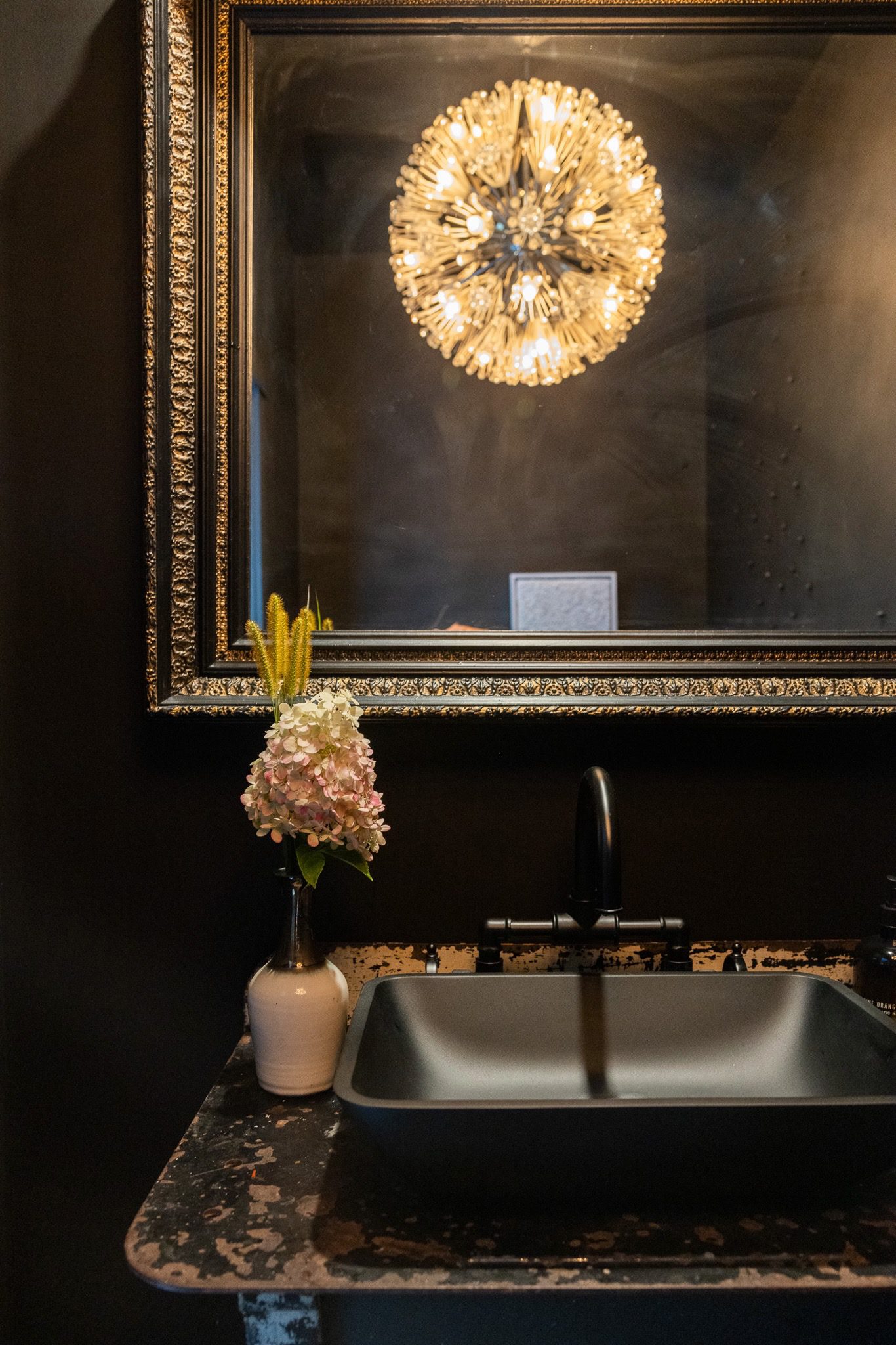 Elegant bathroom with ornate mirror and flowers.