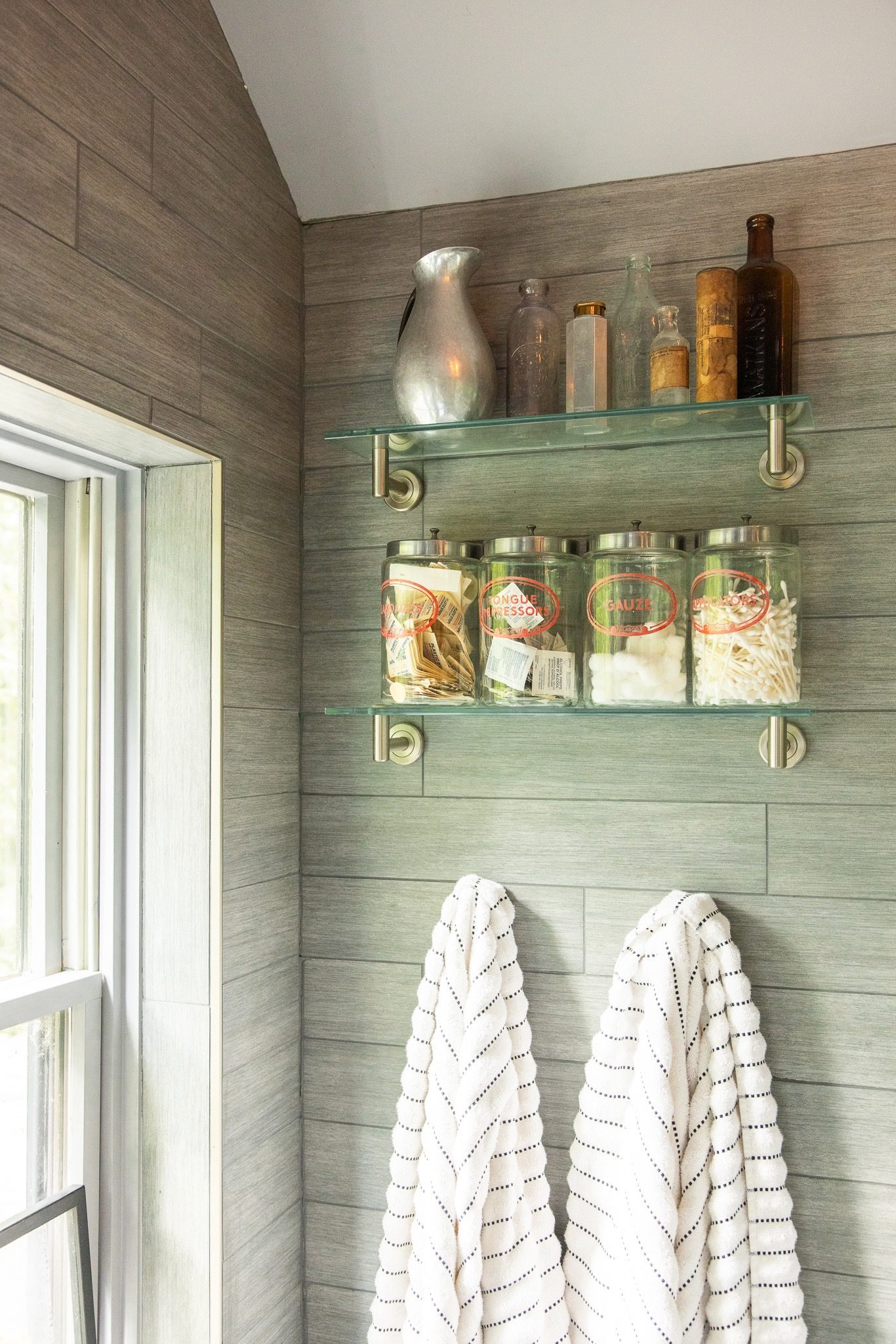 Bathroom shelves with jars and towels hanging.