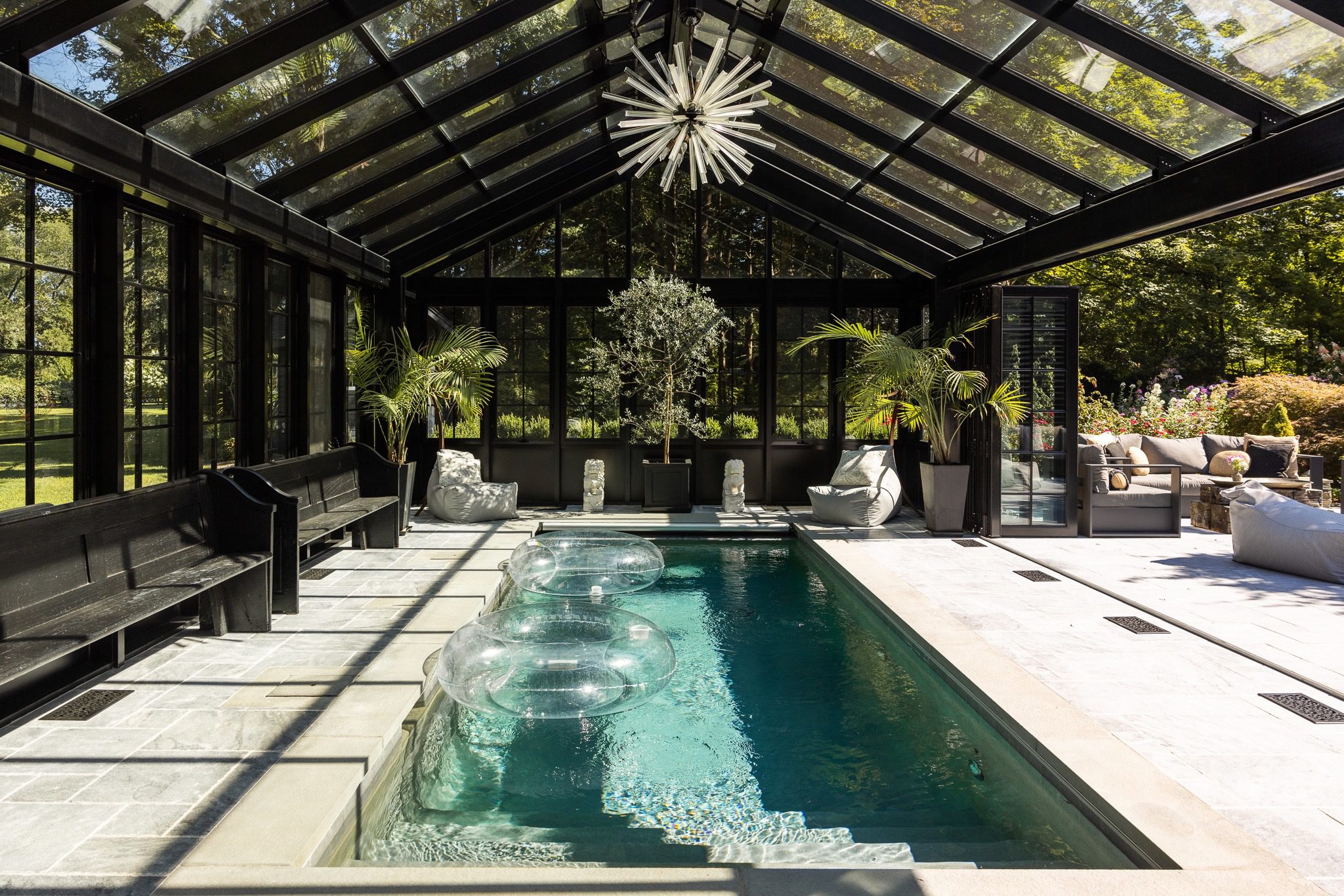 Indoor pool with glass ceiling and plants.