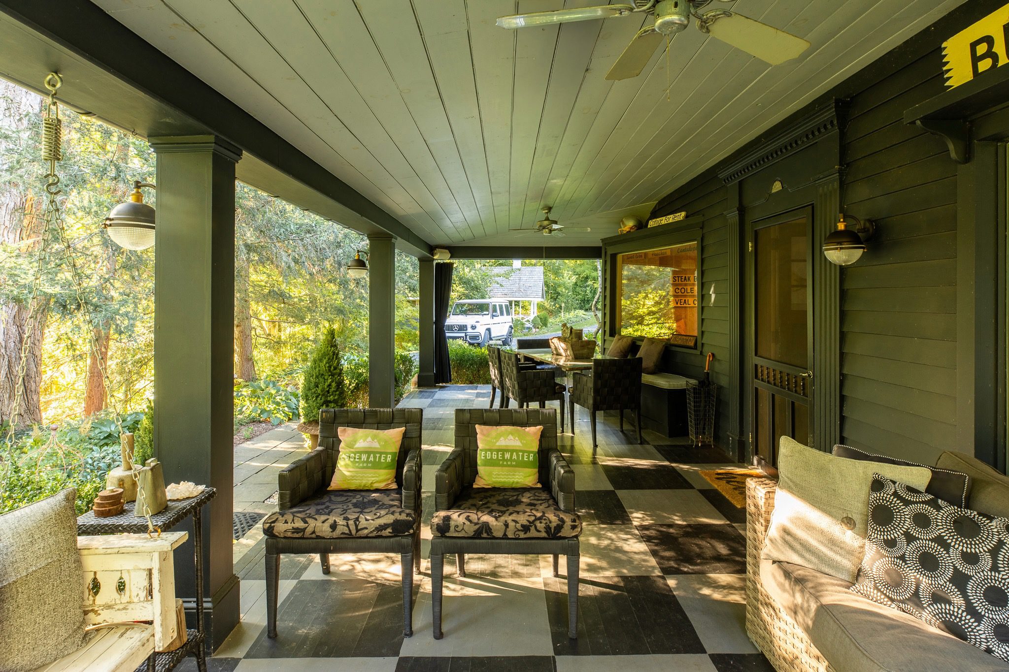 Covered porch with outdoor seating and greenery.
