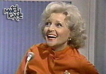Woman in orange sweater, microphone nearby