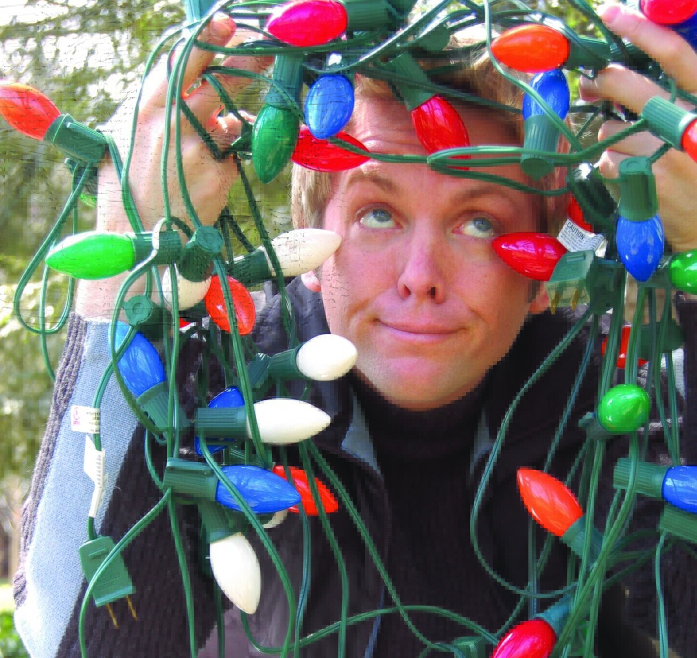 Person tangled in colorful Christmas lights outdoors.