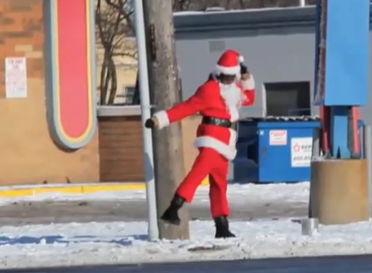 Santa dancing by a pole in snow