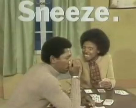 Man sneezing during card game