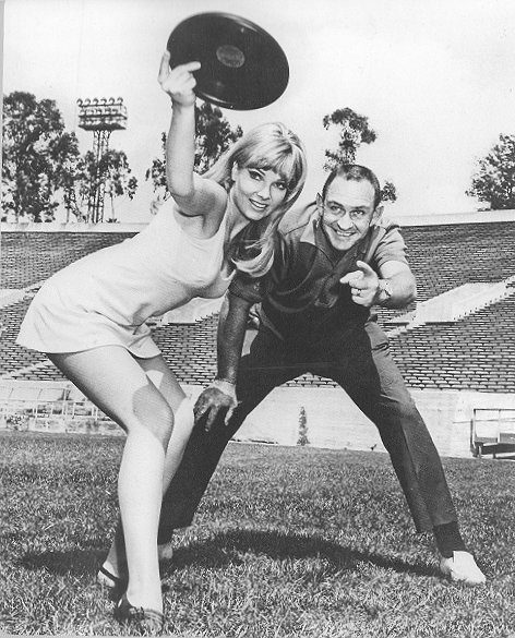 Woman and man playing frisbee in stadium.