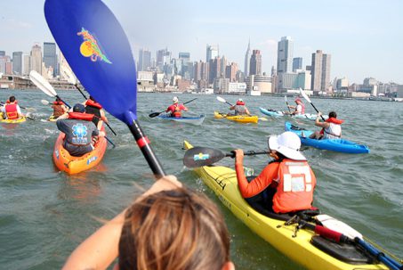 Group kayaking near urban skyline