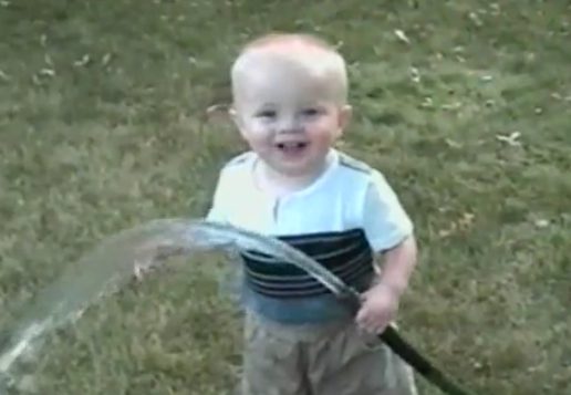 Happy child spraying water on grass