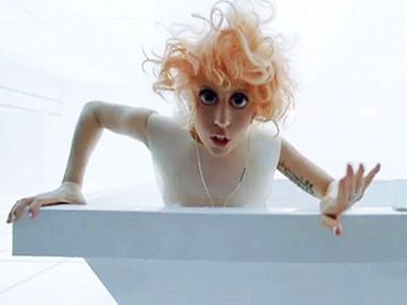 Woman in white room, wide-eyed expression