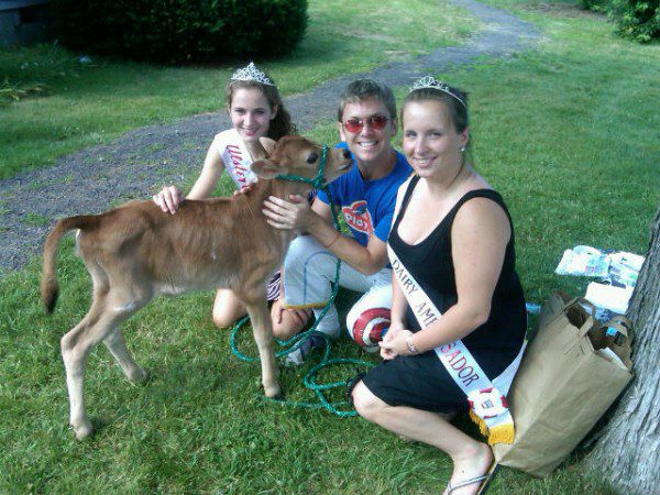 Women with calf outdoors, wearing sashes