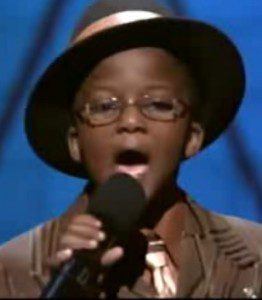 Child singing with microphone and hat