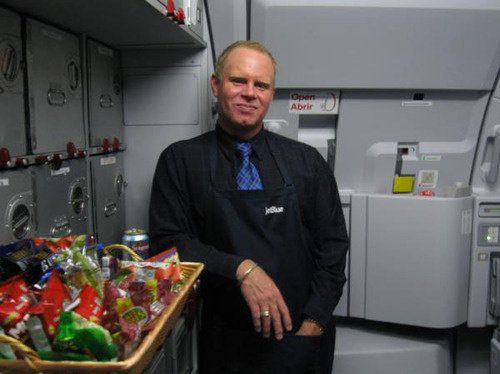 Flight attendant in airplane galley with snacks