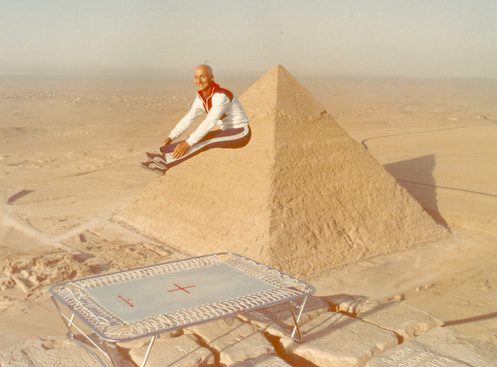 Man jumping on trampoline near pyramid