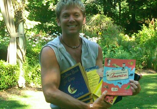 Person displaying books in sunny backyard