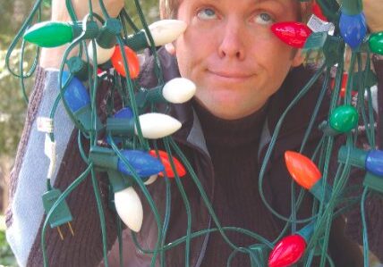 Man playfully wrapped in holiday lights