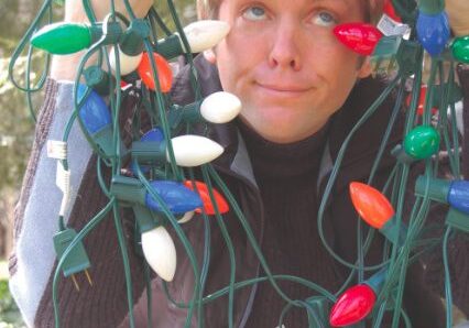Man playfully wrapped in Christmas lights