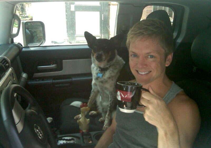 Man with dog in car holding mug