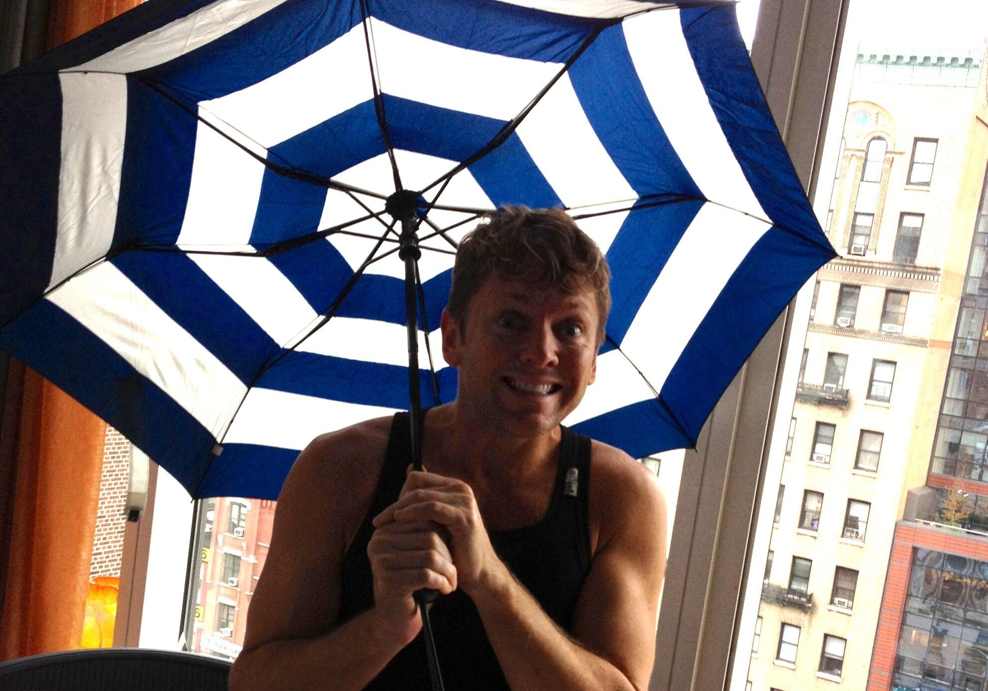 Person playfully posing with an umbrella inside