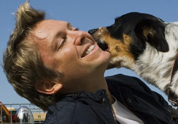 Man smiling with dog licking face