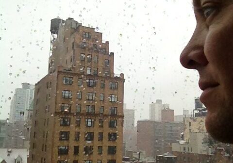 Man gazing out rainy window at cityscape