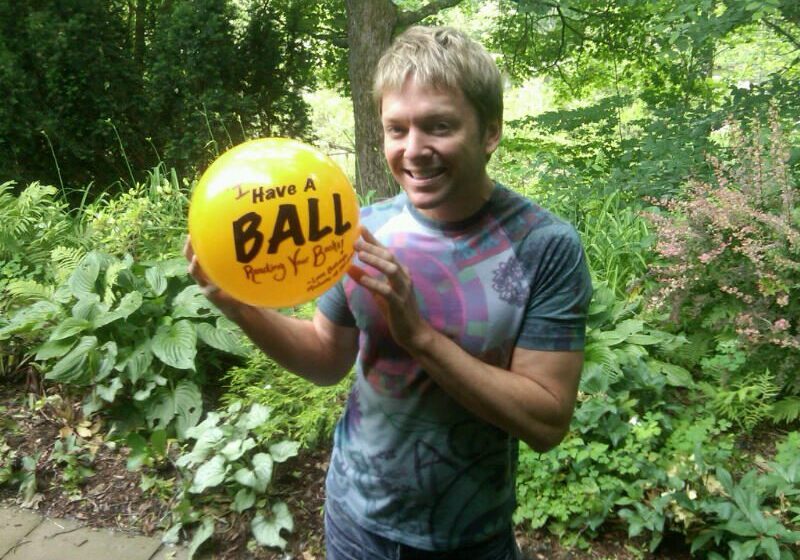 Man holding a yellow balloon outdoors