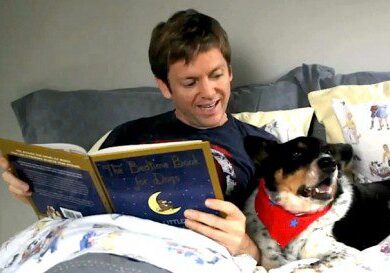 Man and dog reading in bed