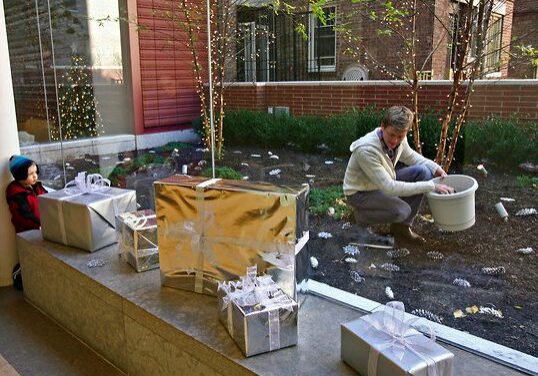 Child watching man decorate garden with gifts