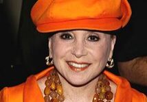 Woman in orange hat and necklace smiling