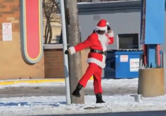 Santa dancing by a pole in snow