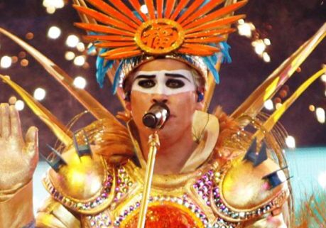 Singer in vibrant, ornate outfit on stage