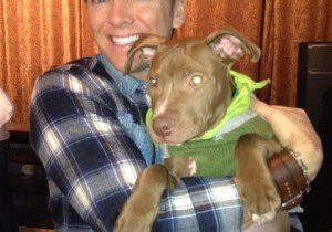 Person with plaid shirt hugging a puppy