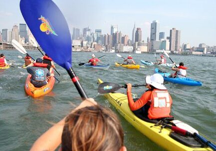 Group kayaking near urban skyline