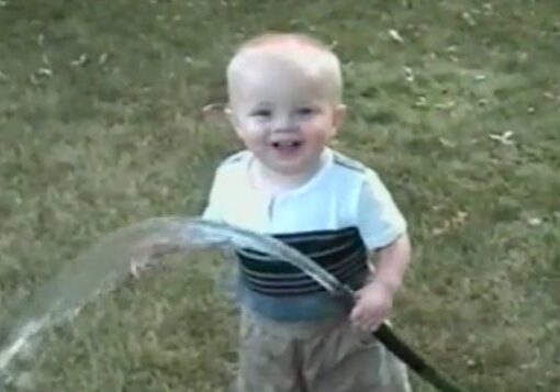 Happy child spraying water on grass